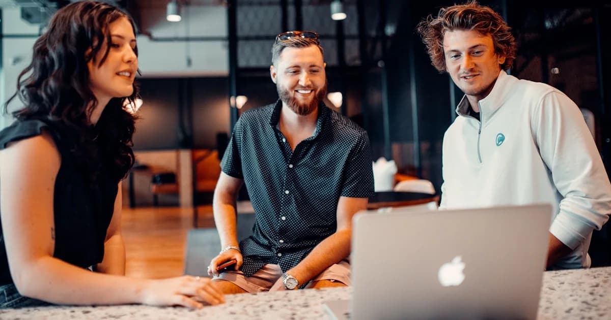 a group of people sitting around a laptop computer