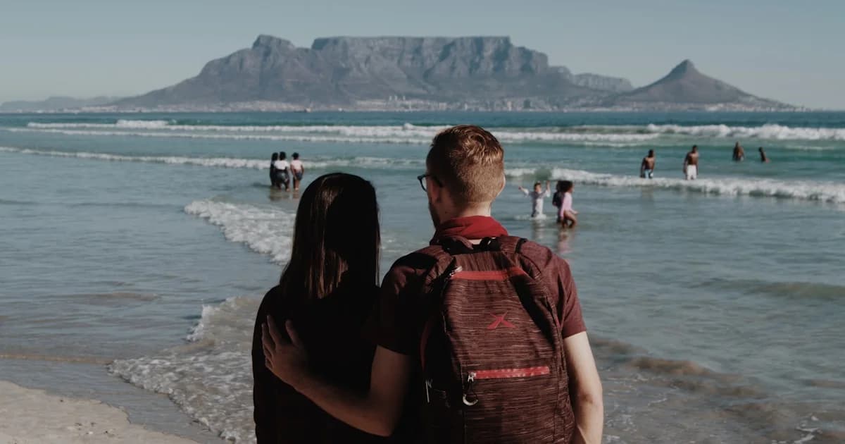 man in red and black backpack sitting on beach during daytime