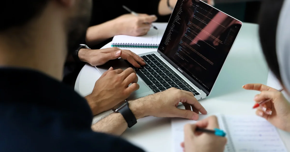 a group of people sitting around a laptop computer