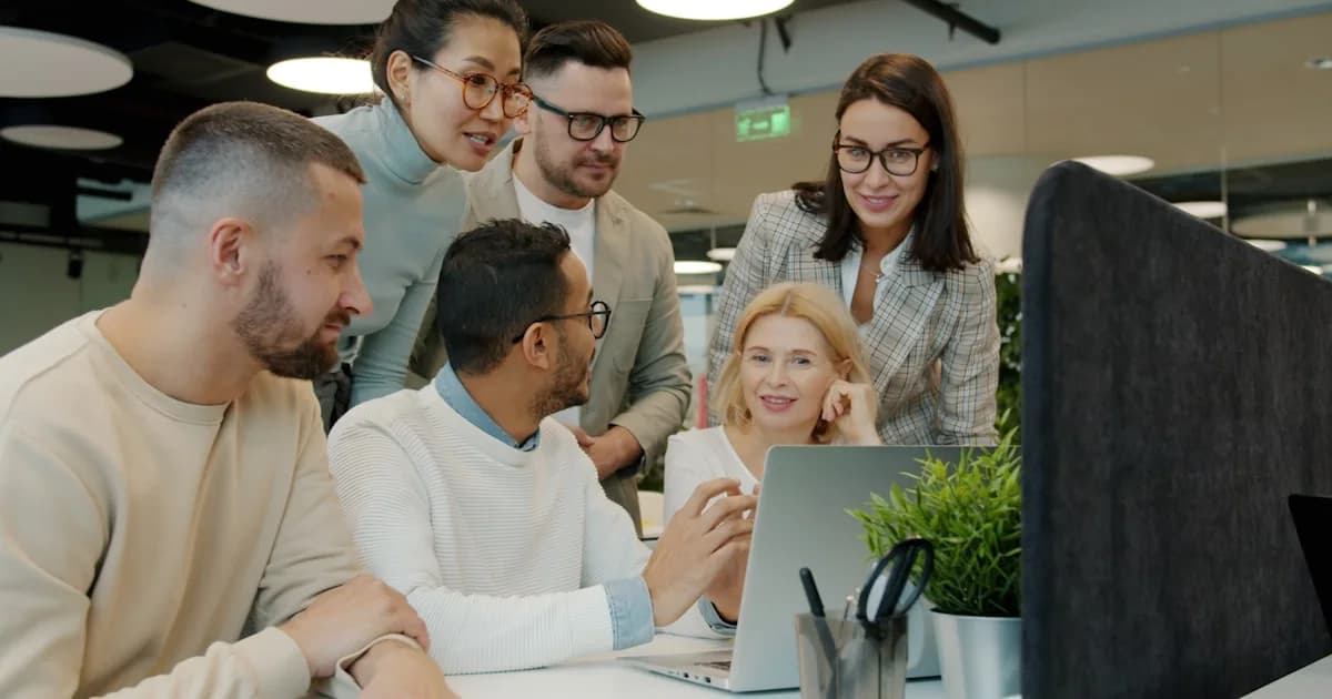 Diverse team collaborating around a laptop in office.