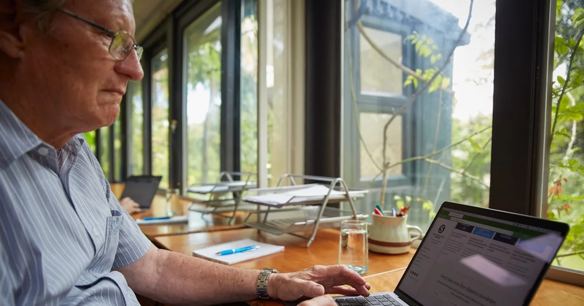 A man sitting at a table using a laptop computer