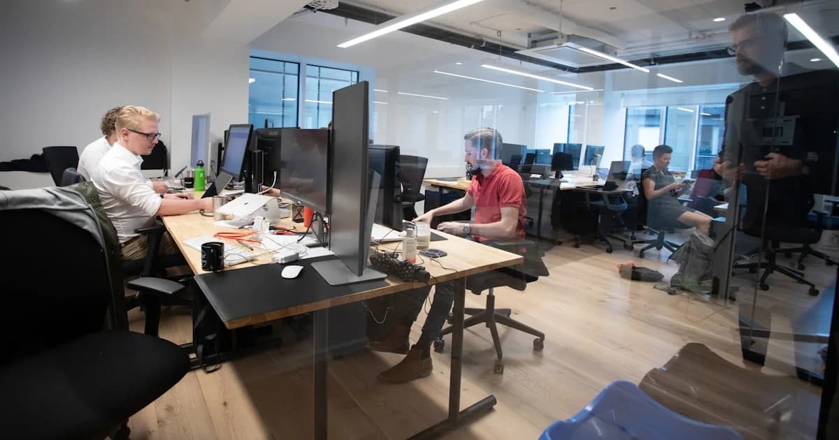 a group of people sitting at desks in an office