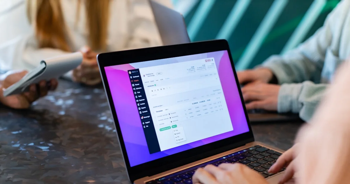 a group of people sitting at a table with laptops
