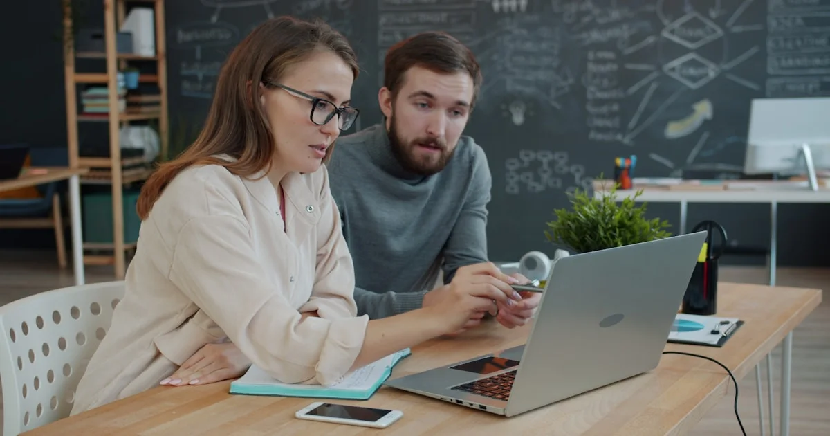Two colleagues collaborating on a project at a laptop.