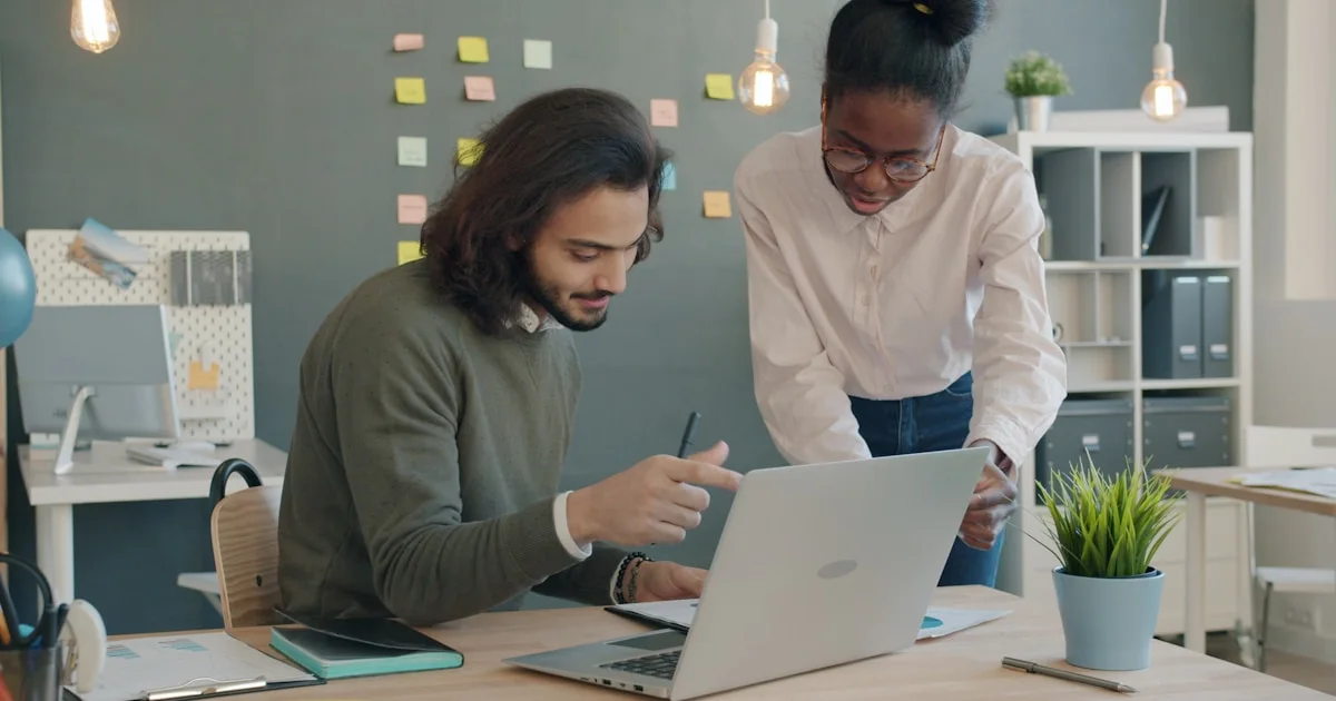 Two colleagues collaborating on a laptop in an office.