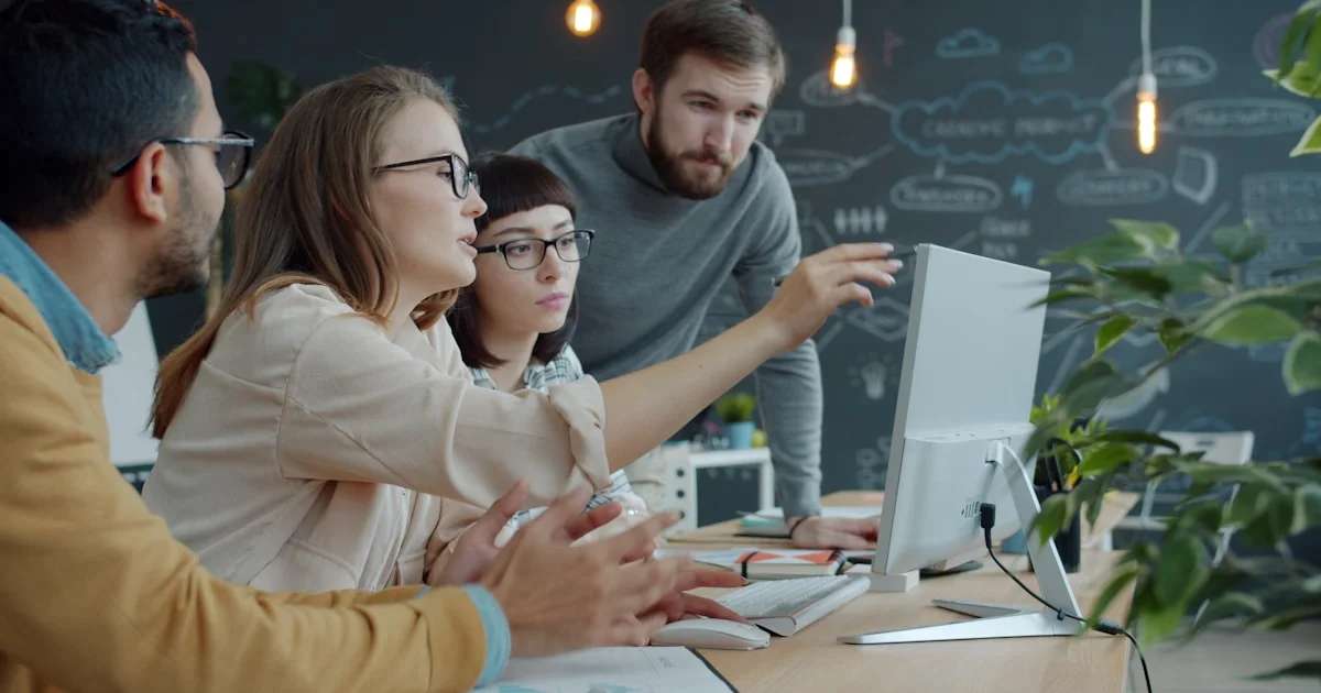 Team collaborating around a computer in an office.