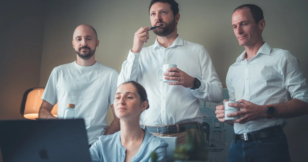 Four people in a room looking at a laptop.