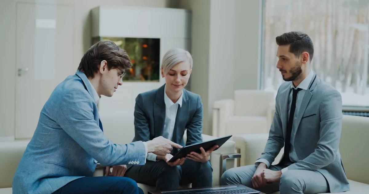 Three professionals discussing a tablet in a modern office.