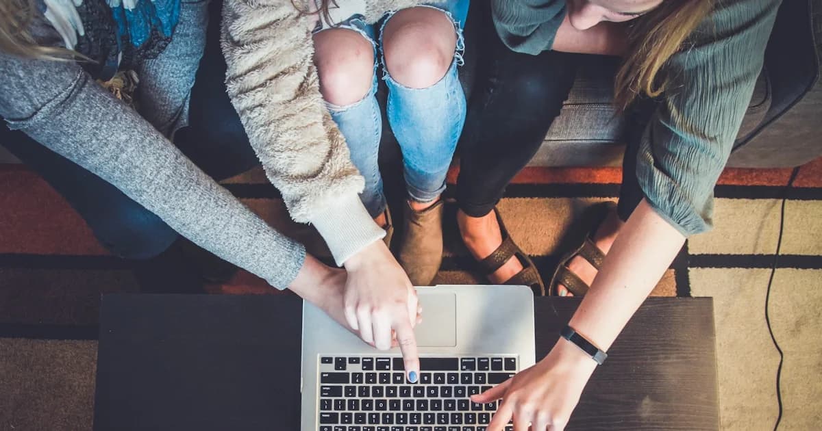 three person pointing the silver laptop computer