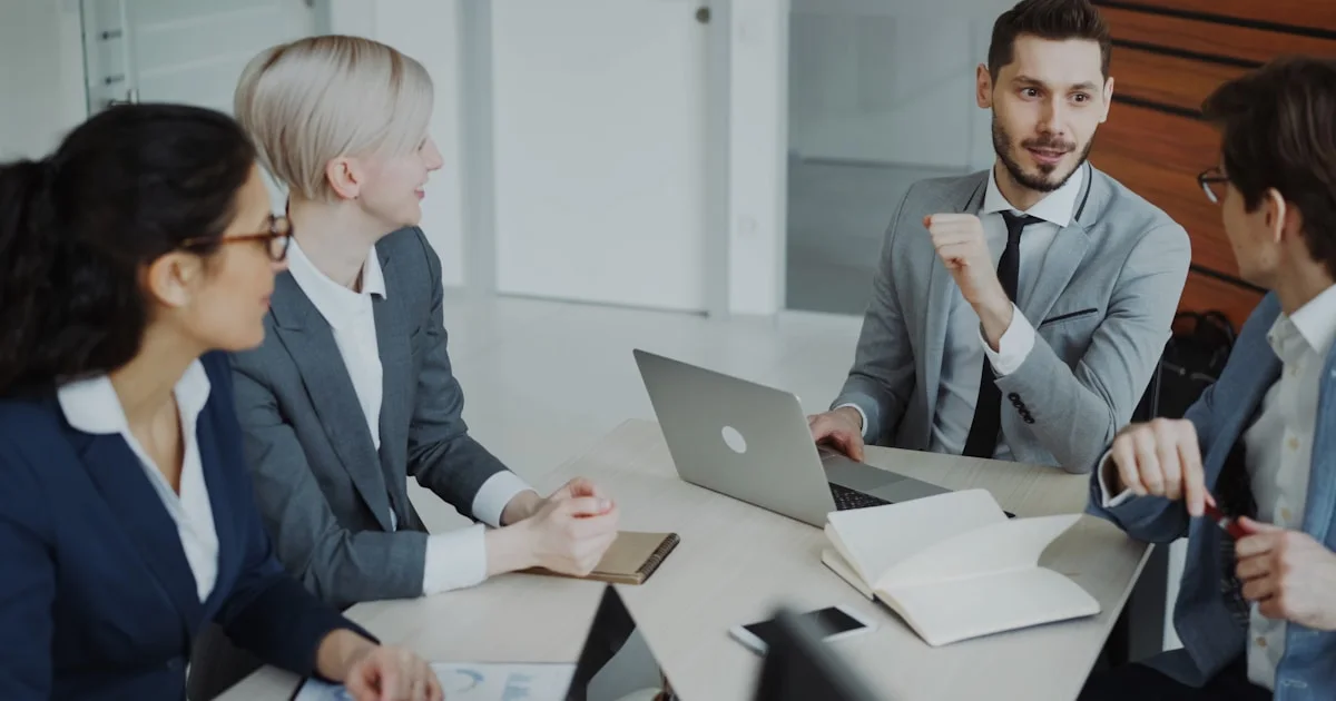 Four professionals in a business meeting around a table.