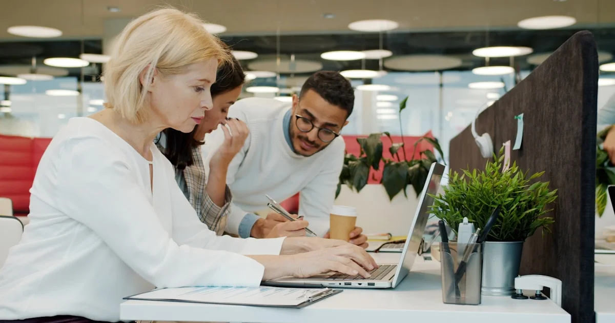 Three people working together on a laptop.