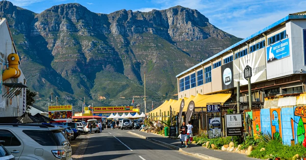 A street with cars parked on both sides and mountains in the background