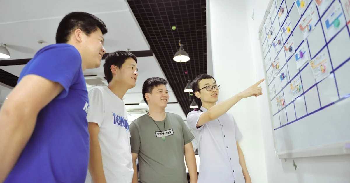 Four men gathered around a whiteboard with sticky notes.