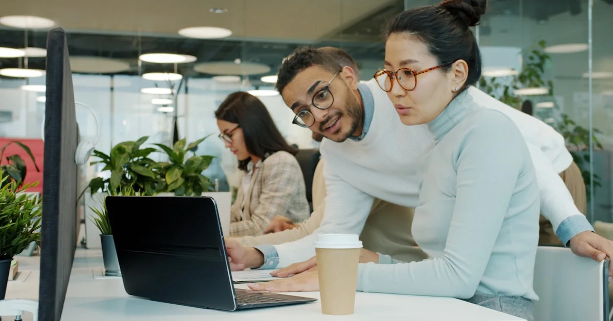 Two colleagues collaborating on a laptop in office.