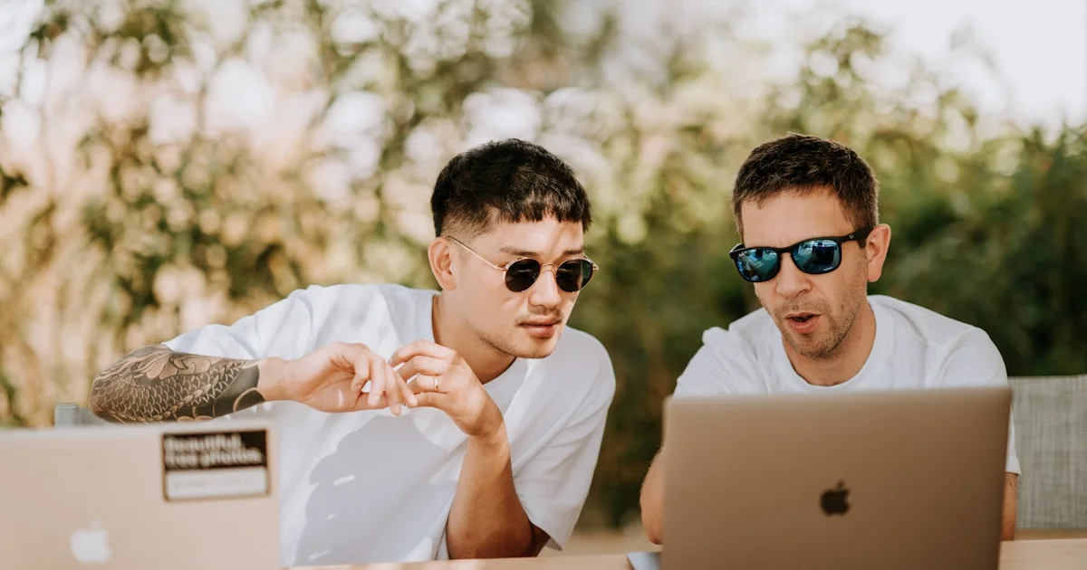 two men using MacBooks