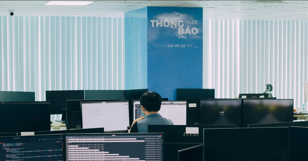 a man sitting at a desk in front of multiple computer monitors