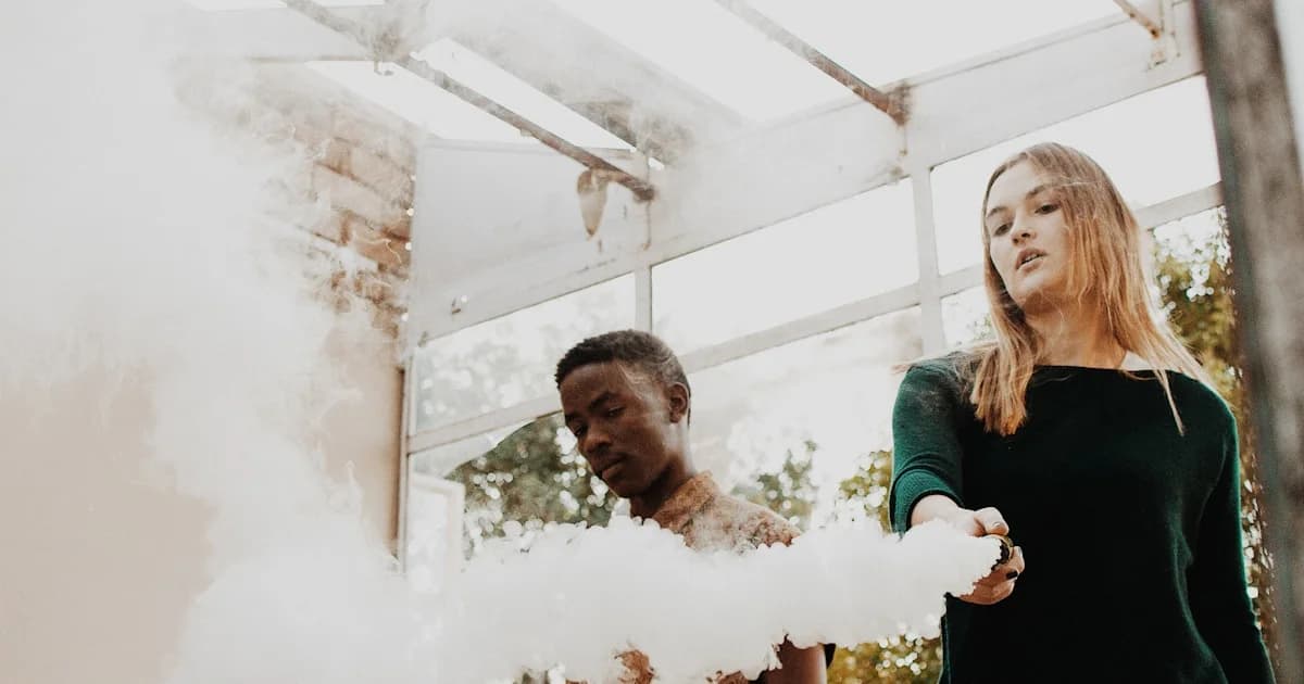 woman holding device emitting smoke beside man