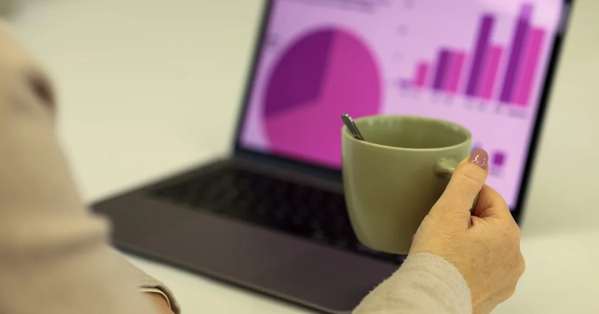 Person working on a laptop with a cup of coffee.
