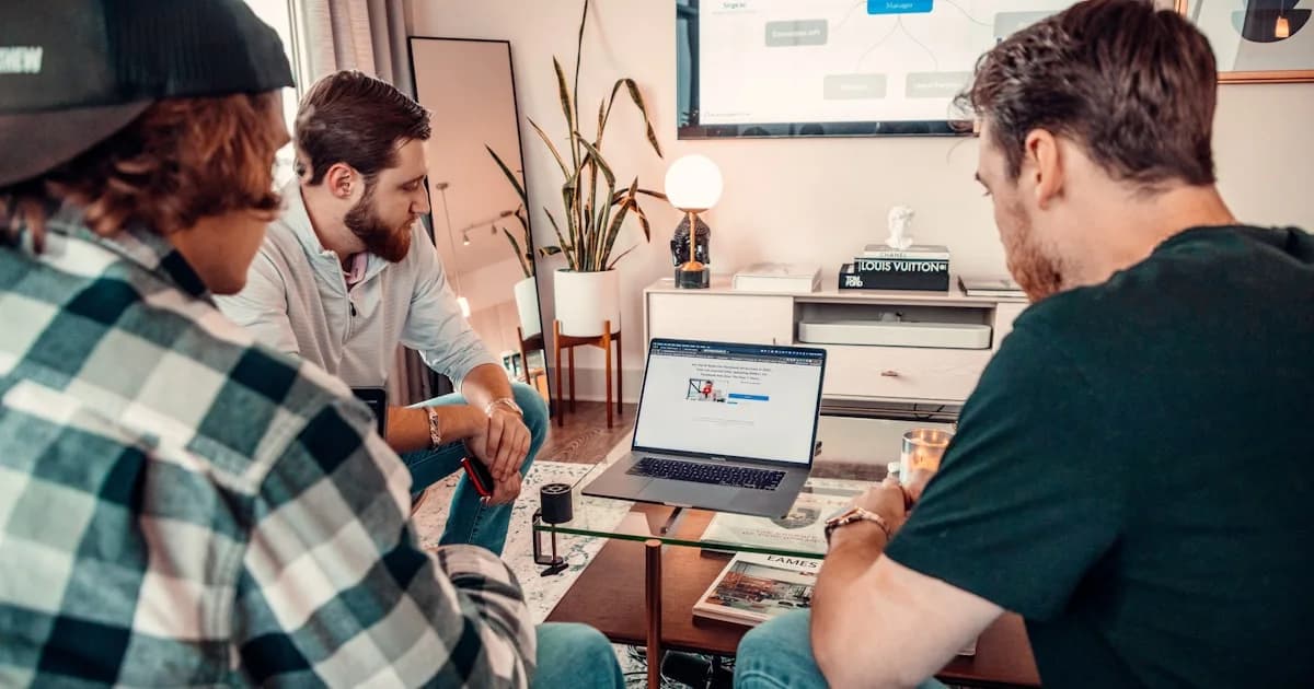 a group of men sitting around a table with a laptop