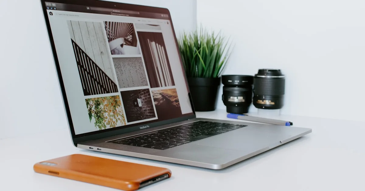 opened MacBook Air beside smartphone, potted plant, and camera lenses