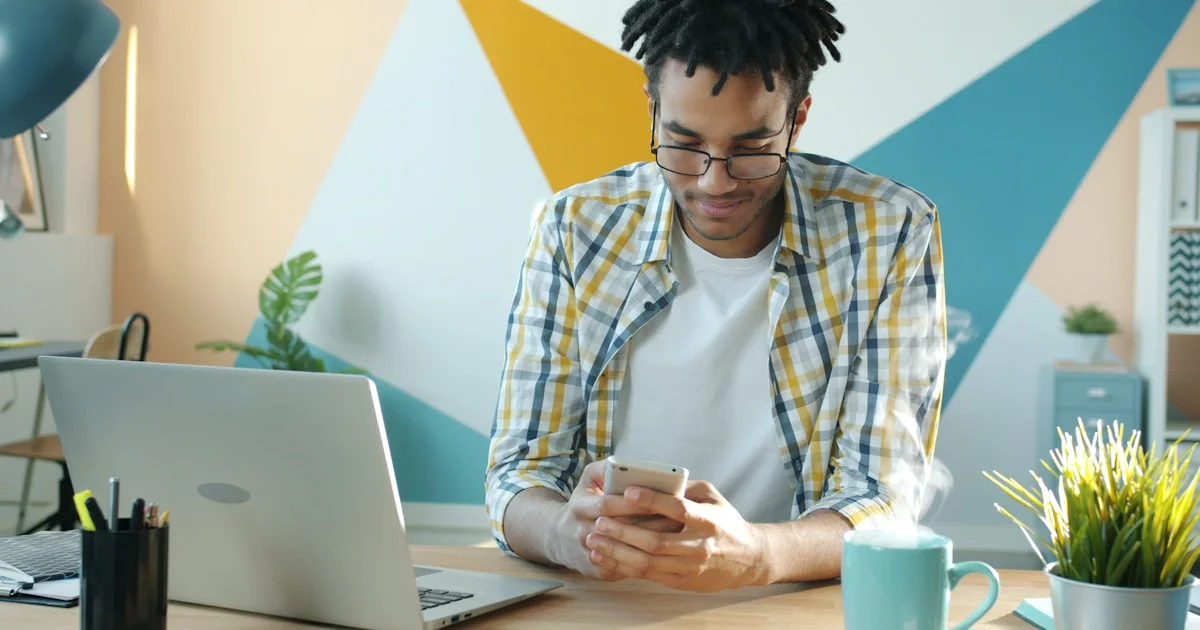 Man in plaid shirt using smartphone at desk