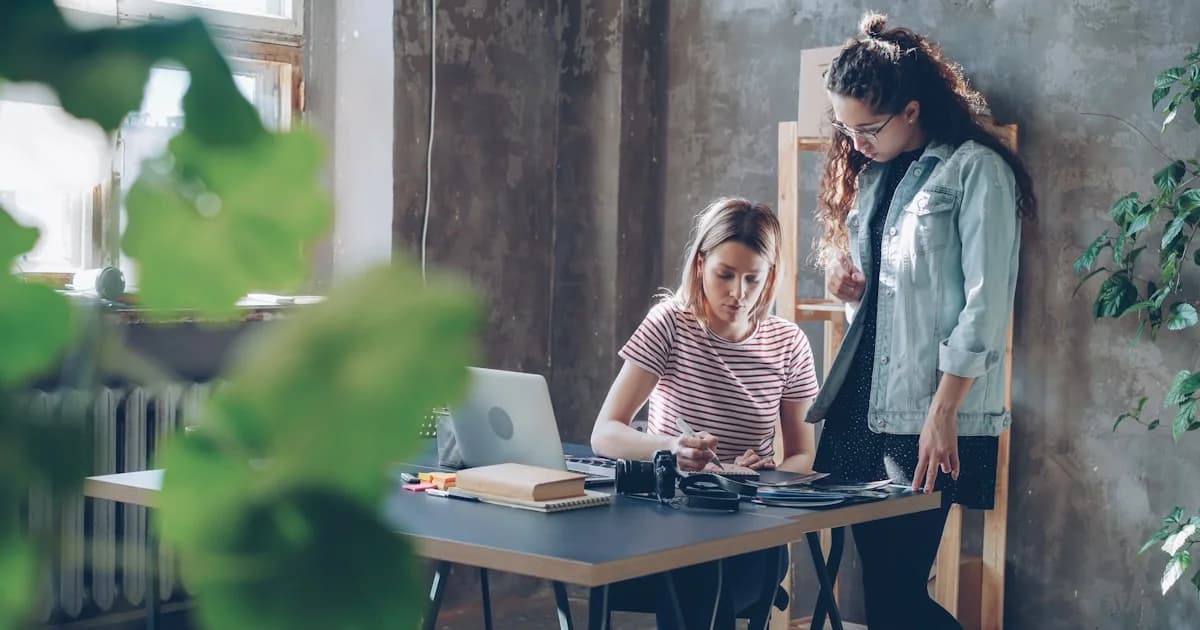 Two women work together at a desk.