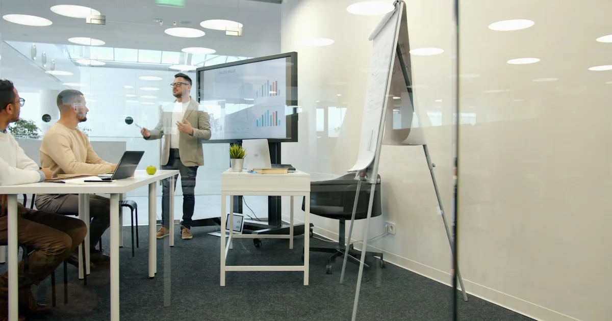 Man presenting to colleagues in a modern office meeting.