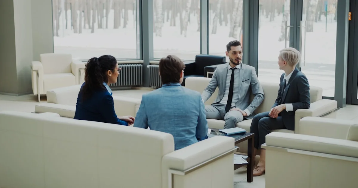 Four professionals in a modern office meeting space.
