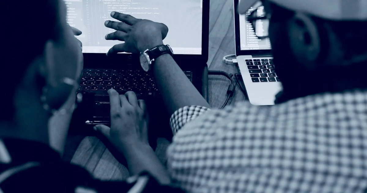 woman using laptop computer beside person wearing hat