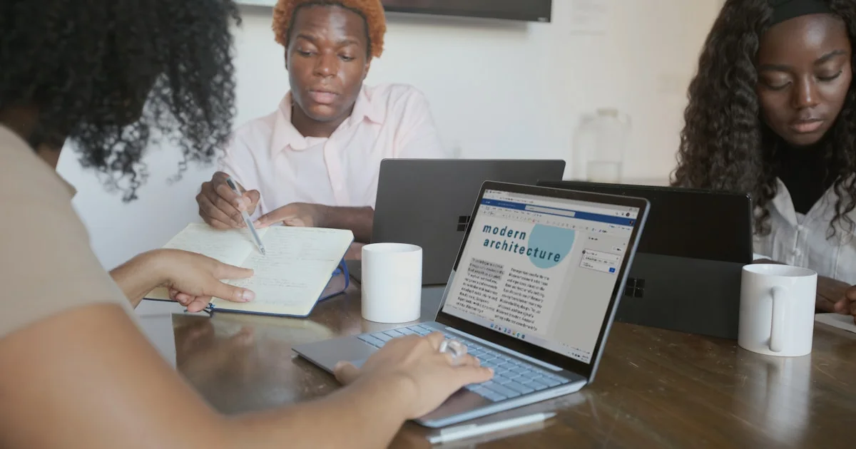 Three people meeting with their Microsoft devices at work