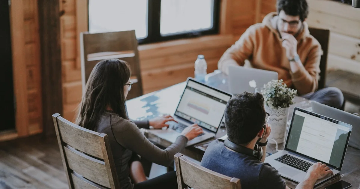 selective focus photography of woman and man using MacBook Pro on table