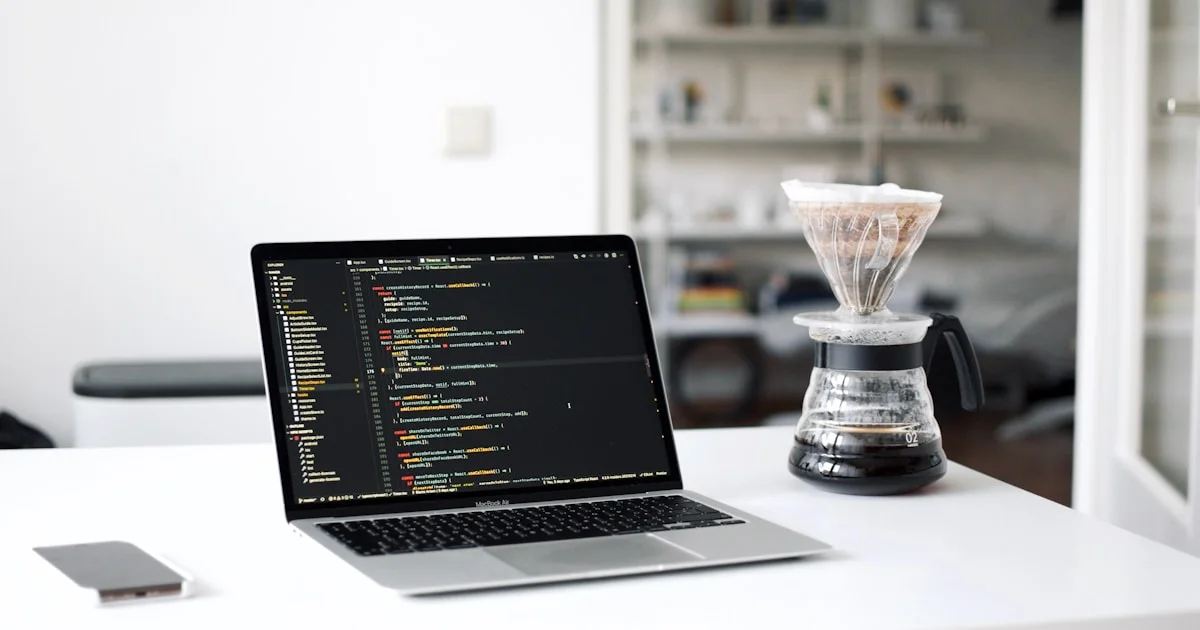 black laptop computer beside clear glass cup