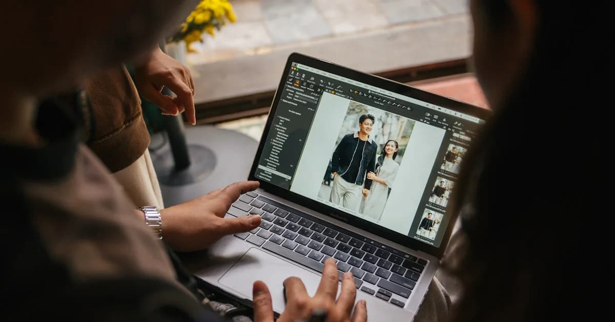 Two people looking at a laptop screen displaying photos