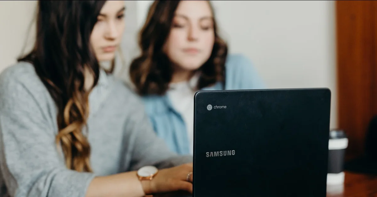 two woman using laptop