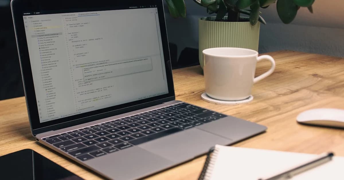 Laptop, notebook, phone, and mug on desk.